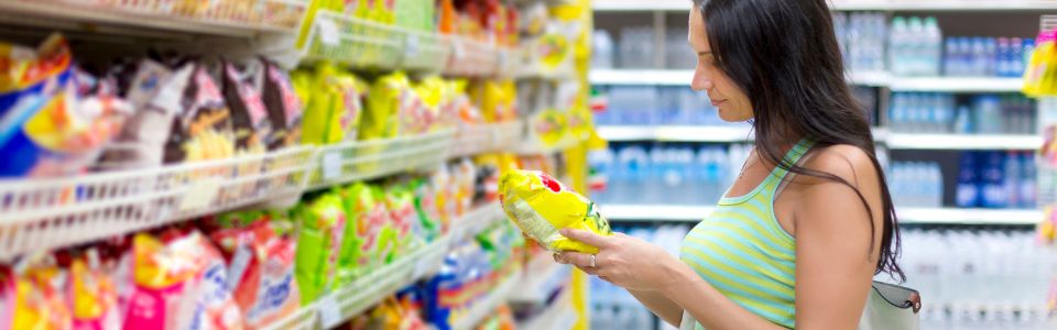 Woman looking at snack packet at supermarket.