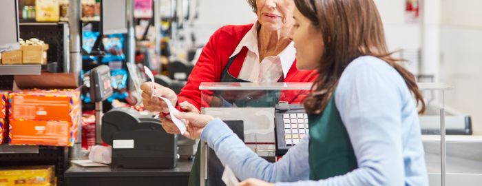 Woman checking receipt at grocery store payment counter.